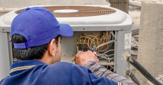 Professional technician fixing the outdoor unit of an air conditioner